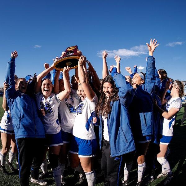 Soccer players lift trophy over their heads in celebration.