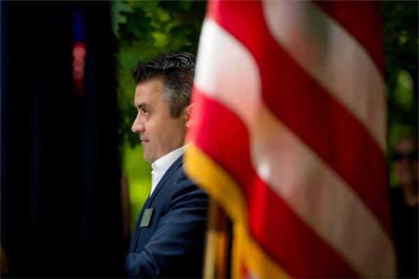 A person is seen from the side with an American flag in the foreground.