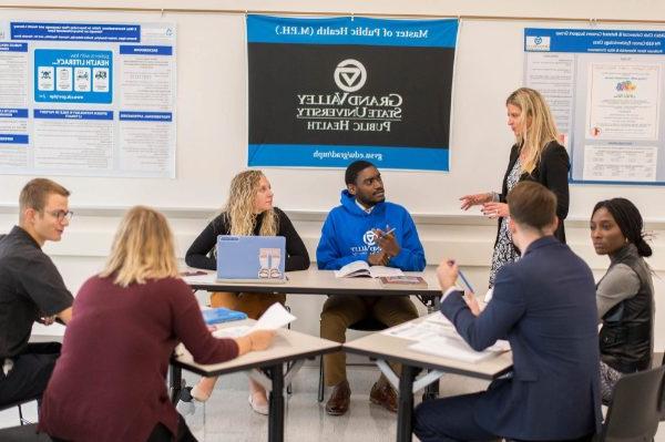 Ranelle Brew stands on the left while students are seated at desks