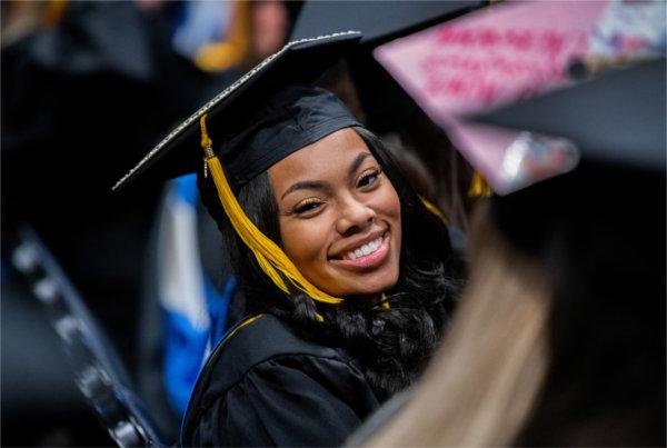 A graduate smiles at the camera.  