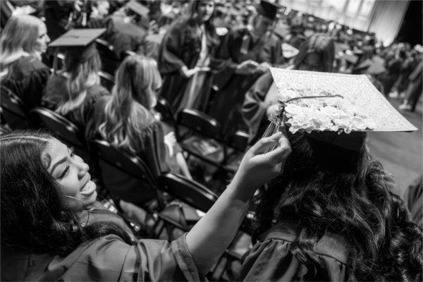  One graduate fixes the tassel of another. 