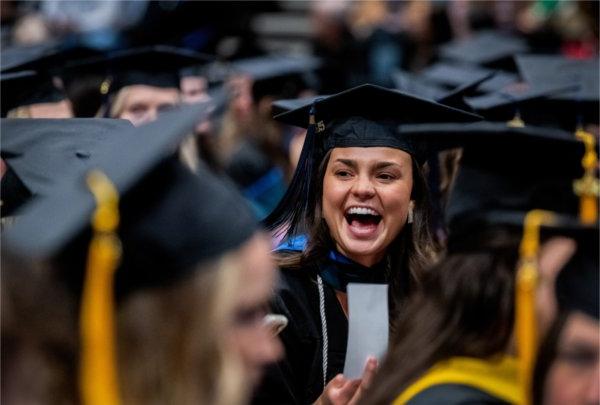  A graduate laughs among other graduates. 