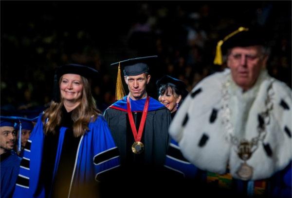  A group wearing academic regalia process in to a ceremony. 