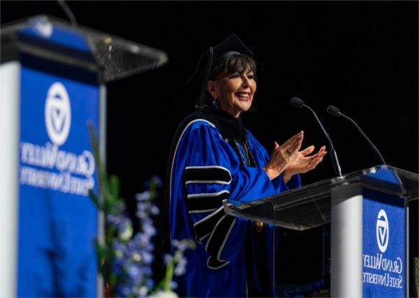  A university president in academic regalia speaks at the lectern. 