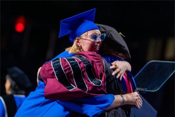  A graduate hugs a dean on stage. 