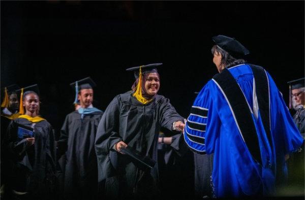  A graduate shakes the hand of the university president after receiving their diploma.