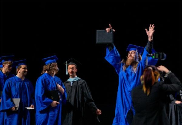   A graduate reacts to receiving their diploma. 