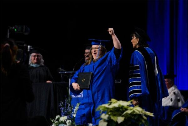   A graduate reacts to receiving their diploma. 