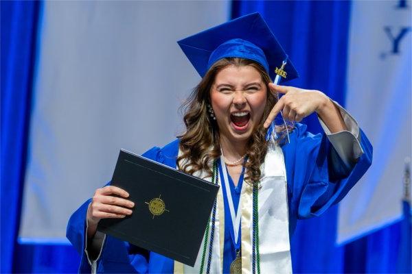   A graduate reacts to receiving their diploma. 