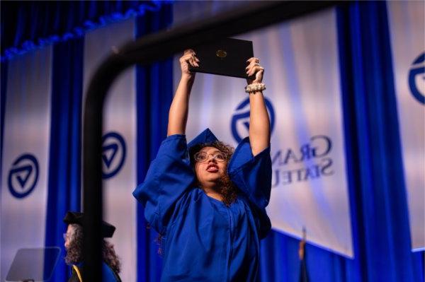   A graduate reacts to receiving their diploma. 