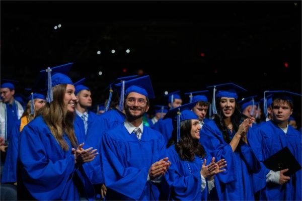  Graduates clap and smile at the end of the commencement ceremony.