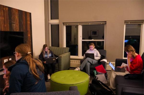 four students site in comfy chairs looking at laptops