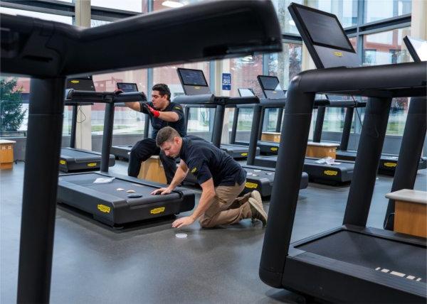 Joseph Steinhauer, left, and Fernando Soriano, both from Technogym, set up new Technogym Run treadmills at the Recreation Center on December 18.