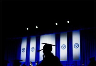 A graduate is silhouetted against blue and white banners.