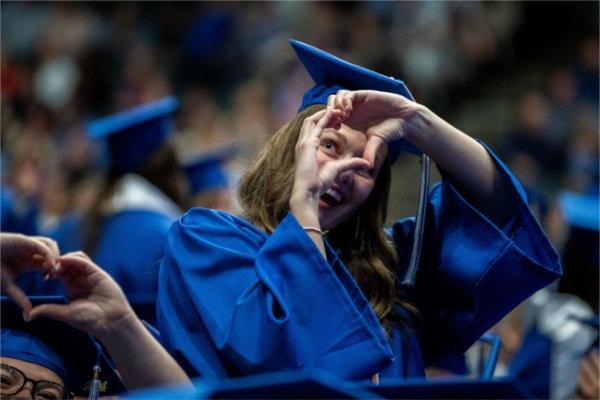  Graduates make heart gestures with their hands. 