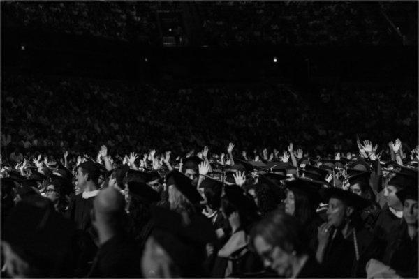  Graduates raise their hands.