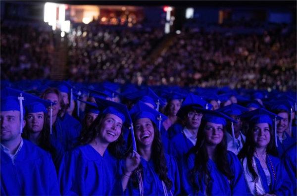  Smiling graduates wearing blue caps and gowns during Commencement.