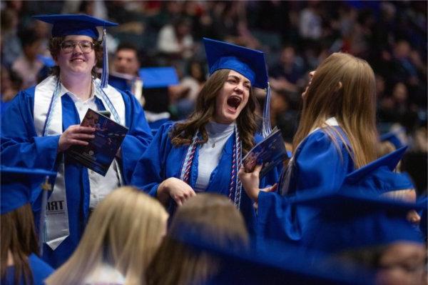  Graduates laugh together during Commencement. 