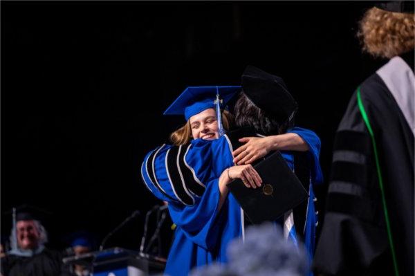  A graduate hugs the university president when receiving their diploma.