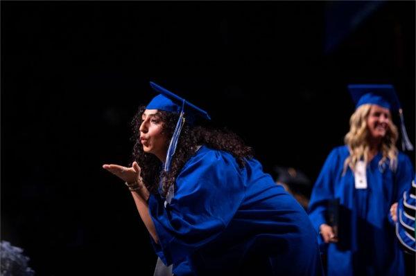 A graduate blows a kiss to the crowd. 