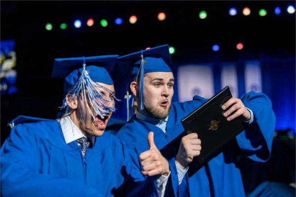   Graduates celebrate as they cross the stage during Commencement. 