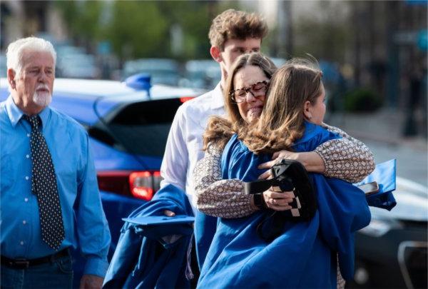  A person cries while hugging a graduate. 