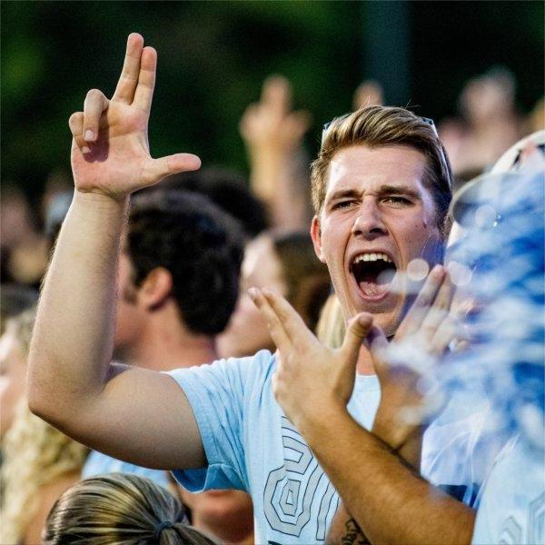 GVSU student shows the Anchor Up hand sign during a football game.