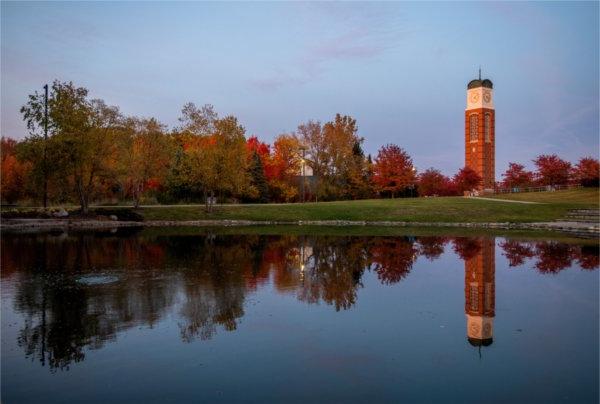 Trees with fall color are also reflected in a pond. The carillon is in the background.