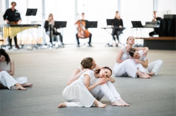  Dancers embrace while performing in front of musicians. 