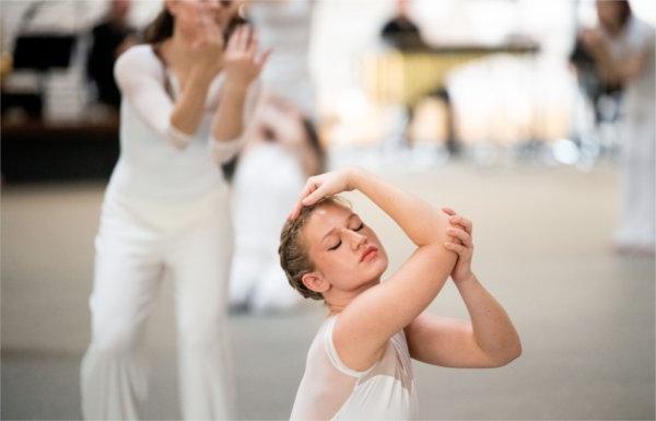  A dancer puts her hands around her head while doing a modern dance performance. 