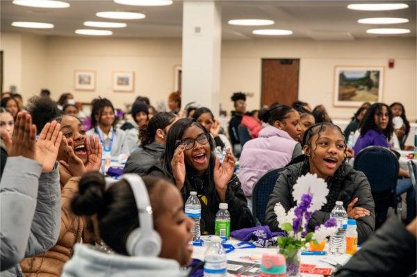 A group of girls clap and cheer after their school was shouted out.