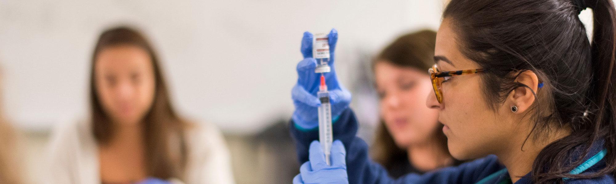 Nursing students practice injections in the simulation lab of Grand Valley's CHS building.